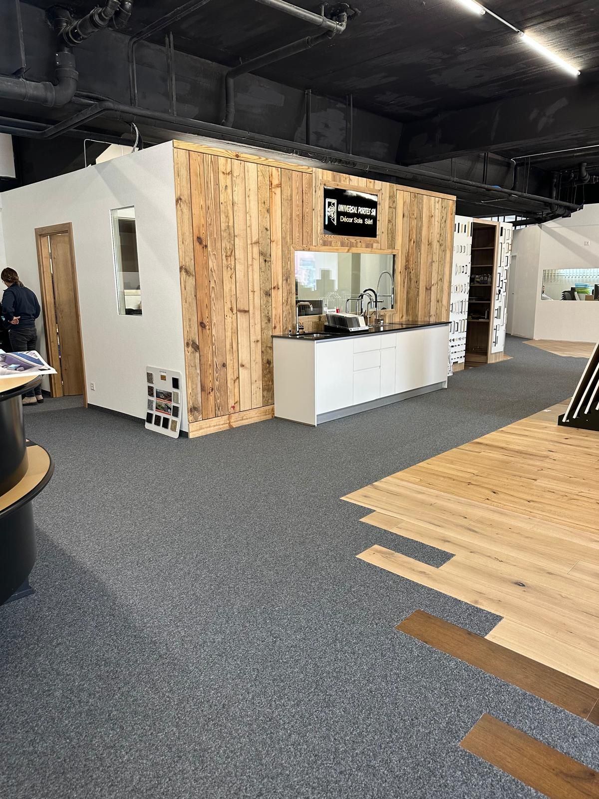 Stand lambrissé dans un showroom intérieur avec comptoir blanc et moquette grise au sol