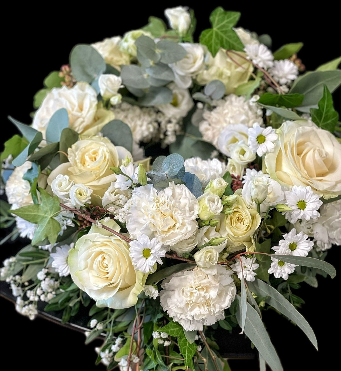 Ein Kranz aus rosa und violetten Blumen auf schwarzem Hintergrund.