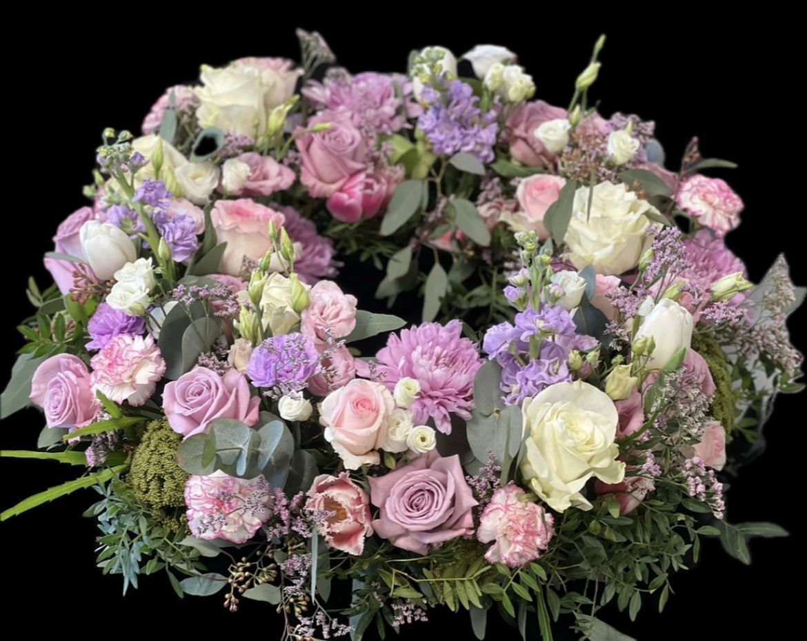 Ein Kranz aus rosa und violetten Blumen auf schwarzem Hintergrund.