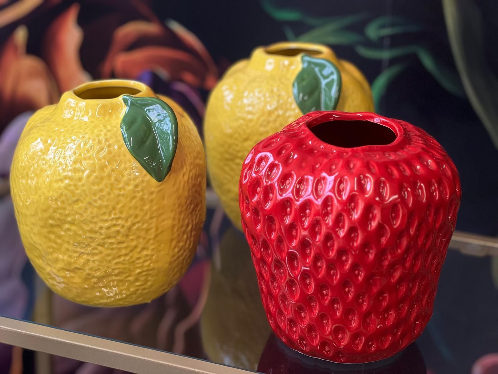 Drei fruchtförmige Vasen: zwei gelbe zitronenförmige Vasen und eine rote erdbeerförmige Vase.
