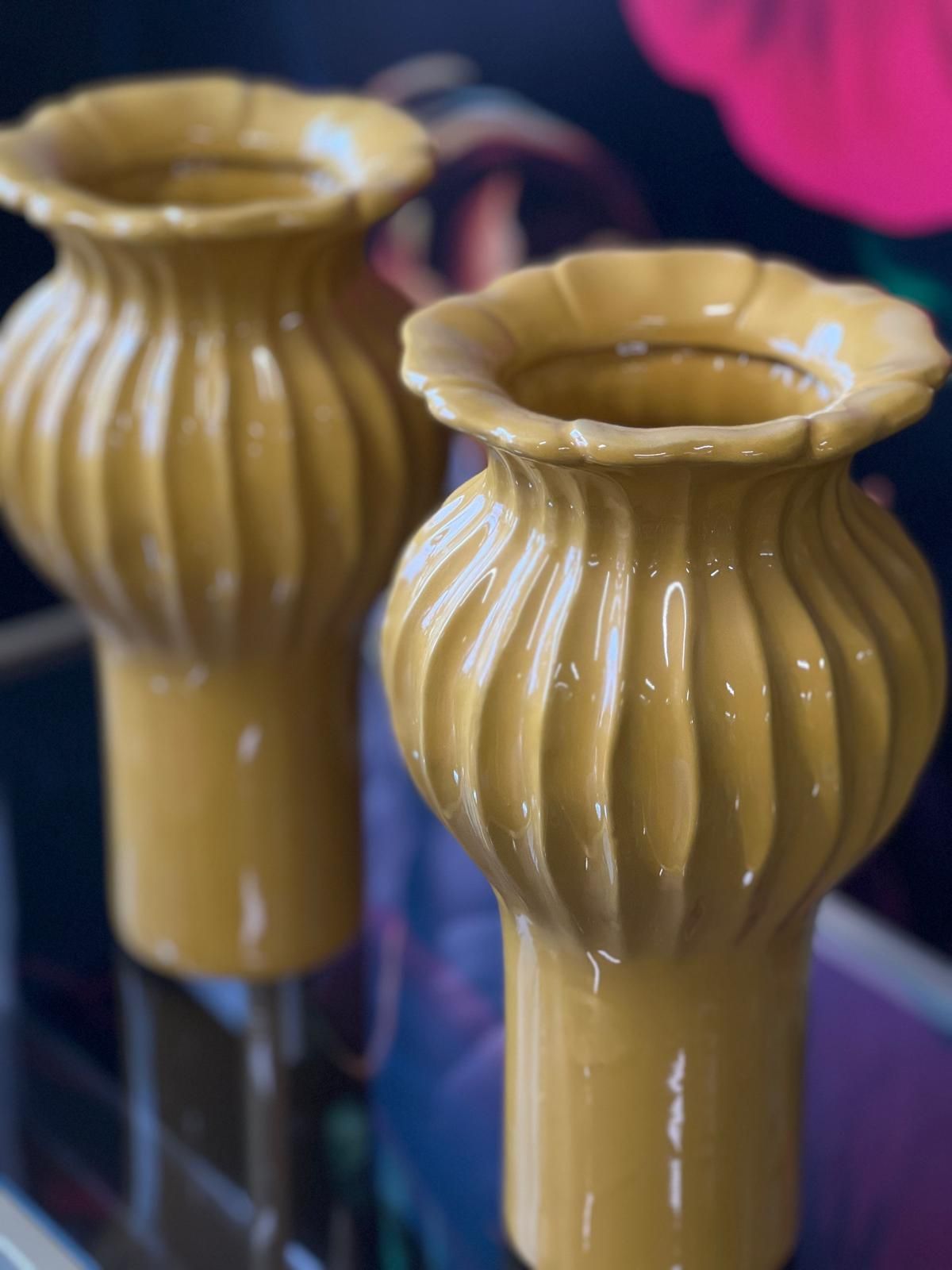 Auf einem Glastisch stehen zwei gelbe Vasen.