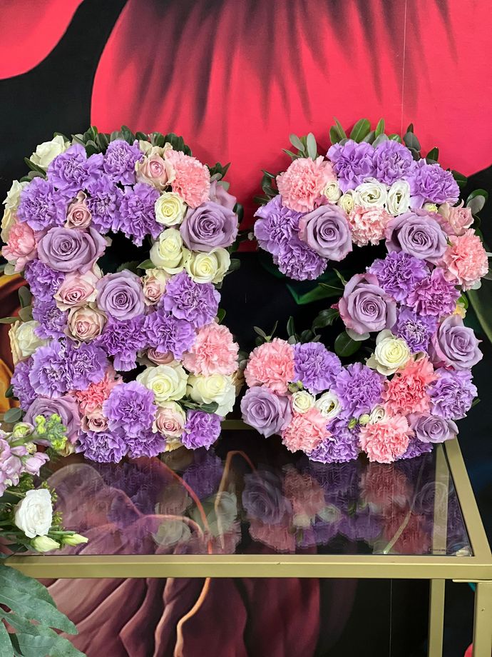 Auf einem Glastisch stehen drei mit Blumen gefüllte Vasen.