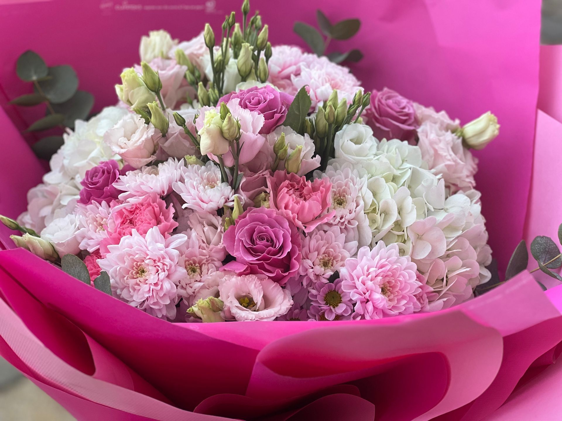 Eine Person hält eine schwarze Schachtel voller rosa und weißer Blumen.