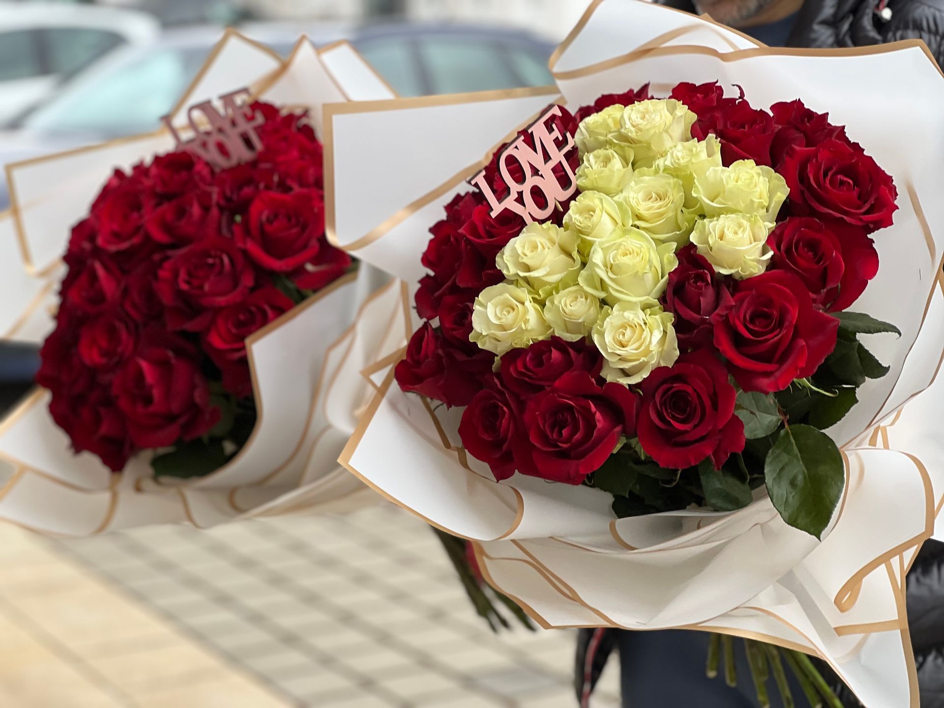 Auf der Motorhaube eines Autos sitzt ein mit Blumen gefüllter Kürbis.