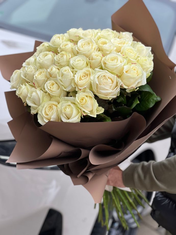 Ein Strauß rosa und weißer Rosen, eingewickelt in rosa Papier