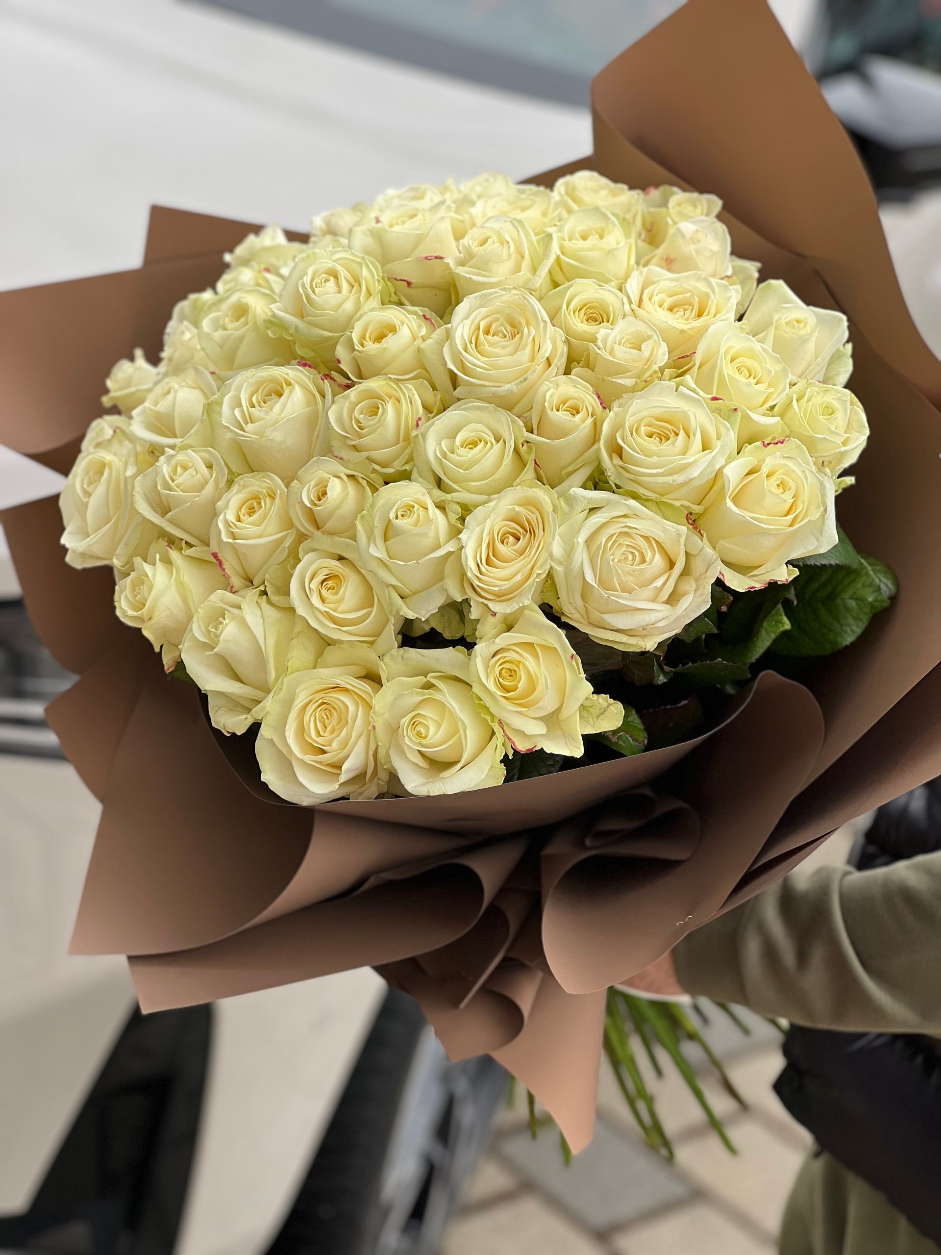 Eine Person hält eine schwarze Schachtel voller rosa und weißer Blumen.