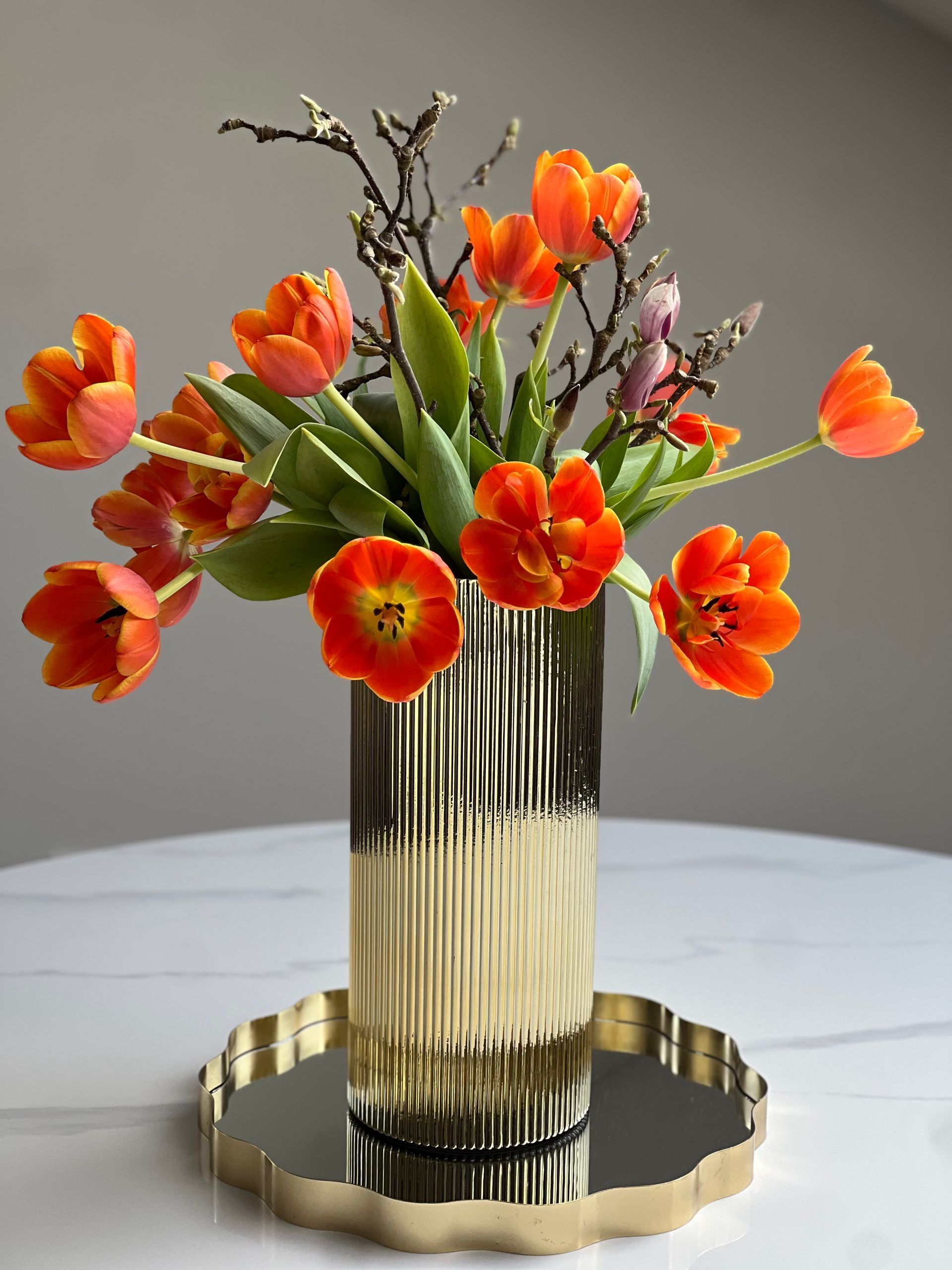 Blumenausstellung: Bunte Topfpflanzen, darunter Rosen, Hortensien und Lavendel, auf gestuften Regalen vor einem Geschäft.