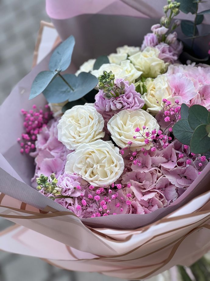 Ein Strauß rosa und weißer Rosen, eingewickelt in rosa Papier