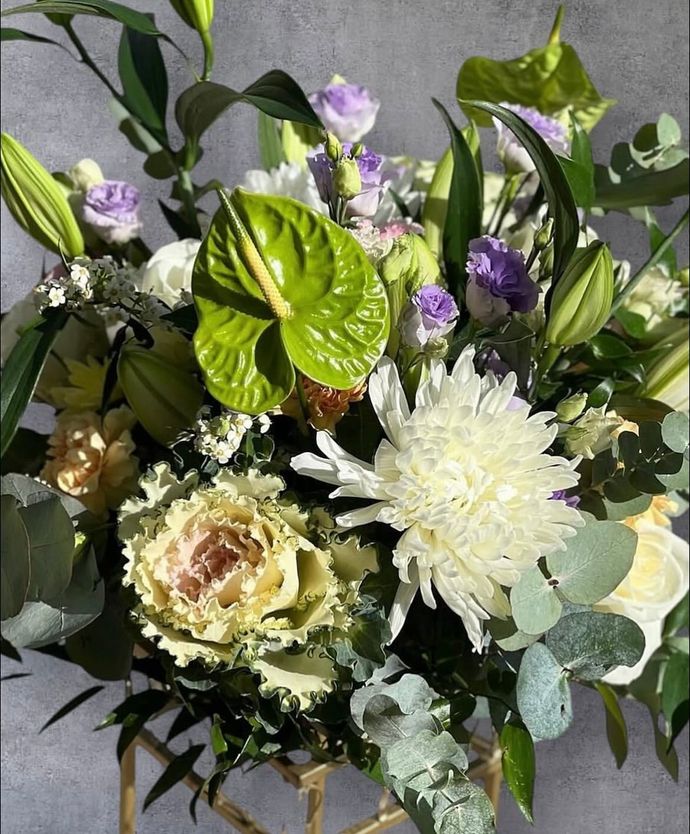 Auf einem Glastisch stehen drei mit Blumen gefüllte Vasen.