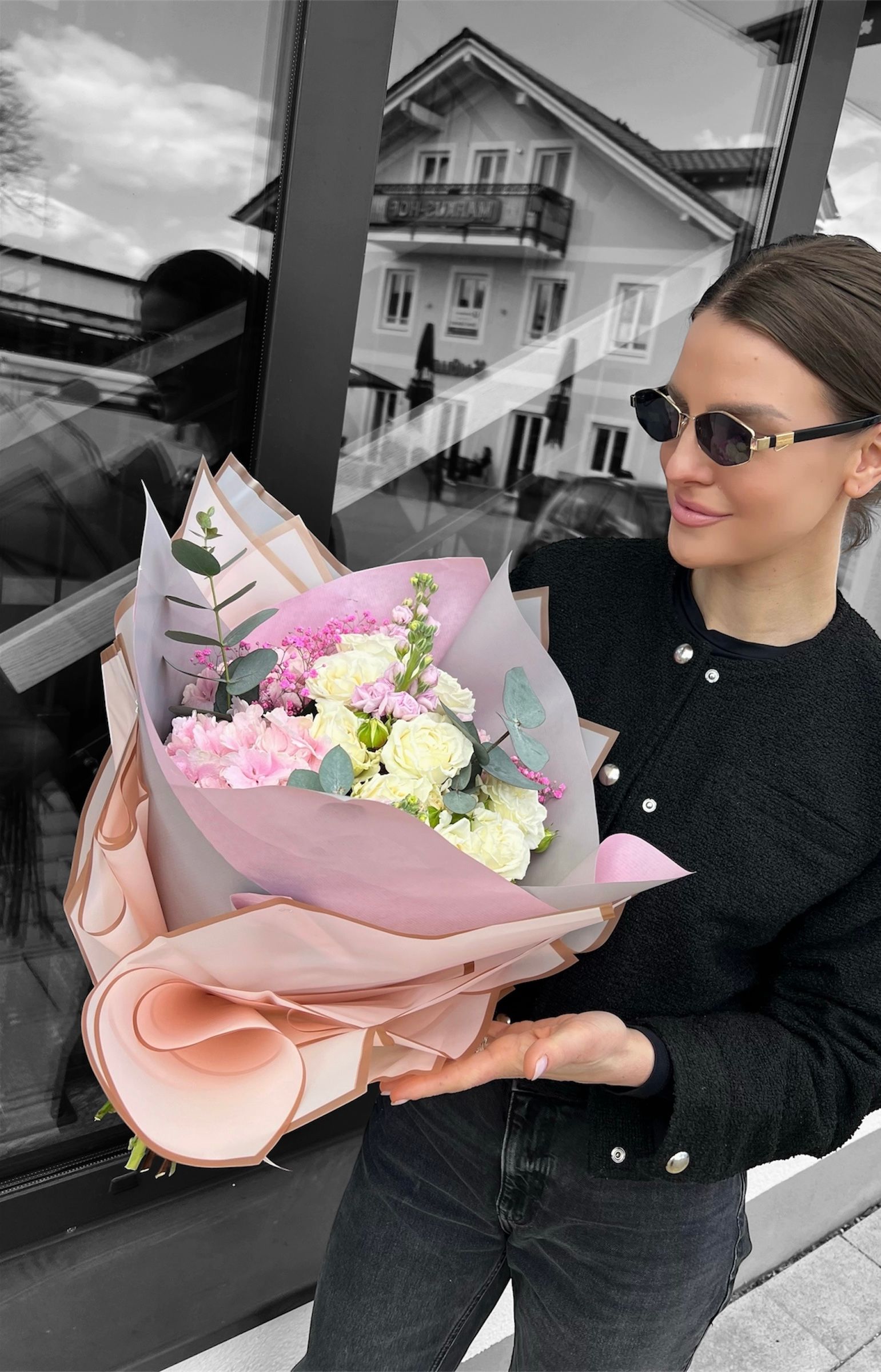 Eine Person hält eine schwarze Schachtel voller rosa und weißer Blumen.