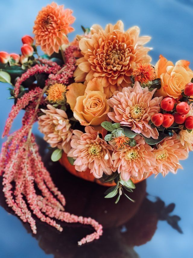 Ein Blumenstrauß in einem Kürbis auf einem Tisch