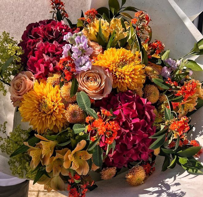 Eine Person hält einen Strauß bunter Blumen