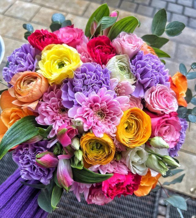 Eine Person hält einen Strauß bunter Blumen