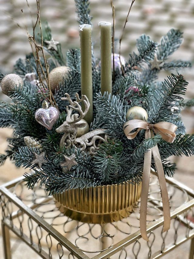 Auf einem Tisch steht ein Weihnachtsarrangement mit Kerzen und Dekorationen.