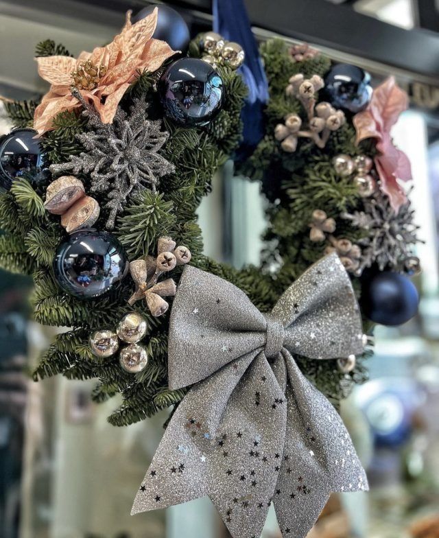 An einer Wand hängt ein Weihnachtskranz mit einer Schleife.