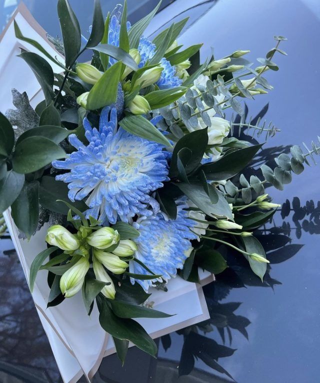 Ein Strauß blauer und weißer Blumen mit grünen Blättern