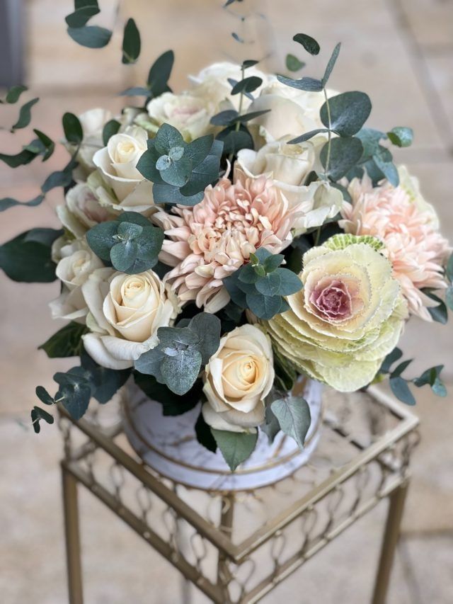 Auf einem Tisch steht eine mit Blumen gefüllte Vase.