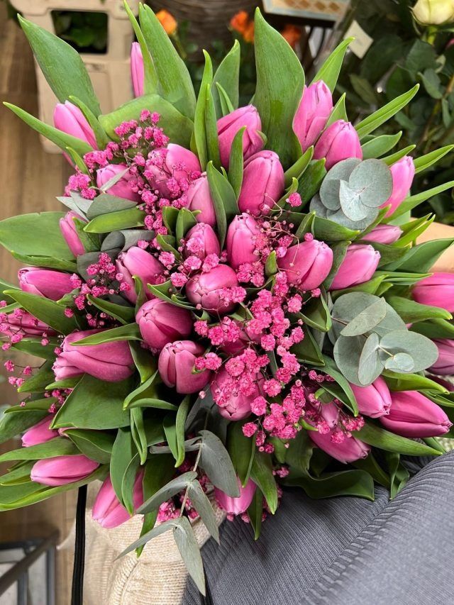 Eine Nahaufnahme eines Straußes rosa Blumen mit grünen Blättern.