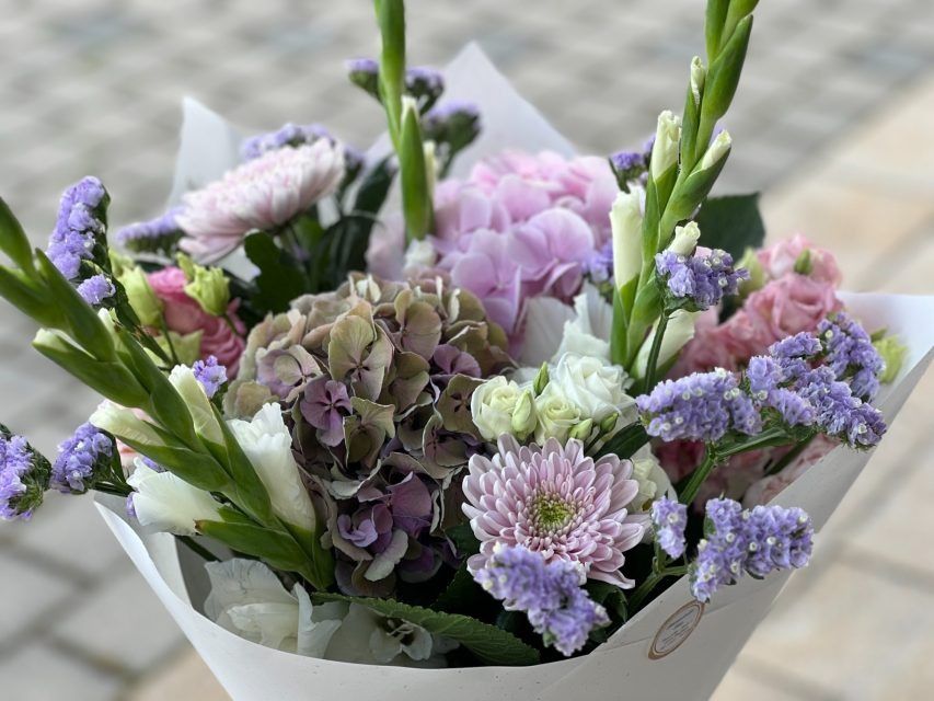 Eine Nahaufnahme eines in weißes Papier eingewickelten Blumenstraußes.