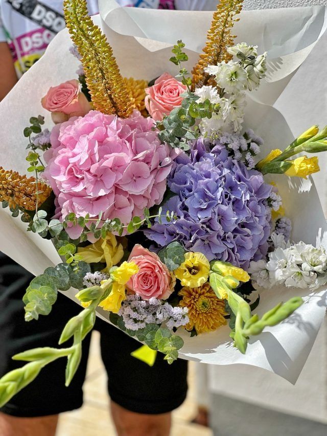 Eine Person hält einen großen Blumenstrauß.