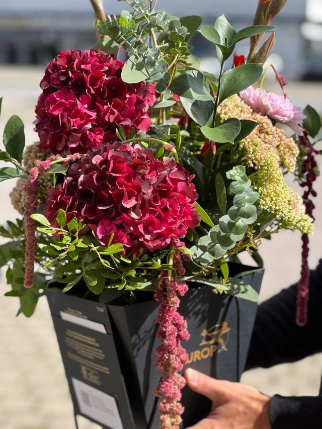 Eine Person hält einen Blumenstrauß in einer schwarzen Schachtel.