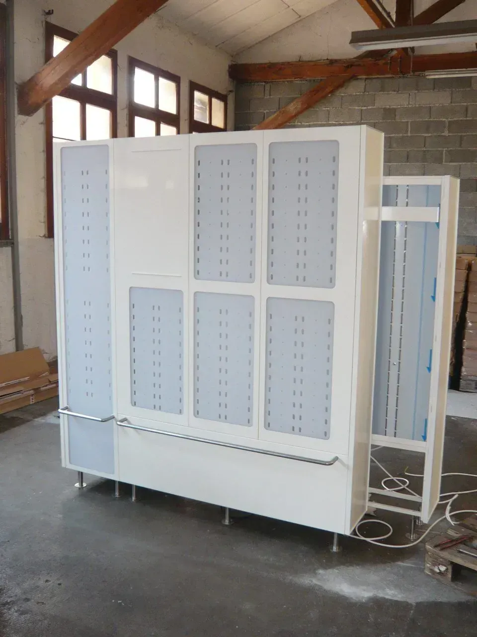 Vestiaire en métal blanc avec de nombreuses petites ouvertures, dans un environnement industriel.