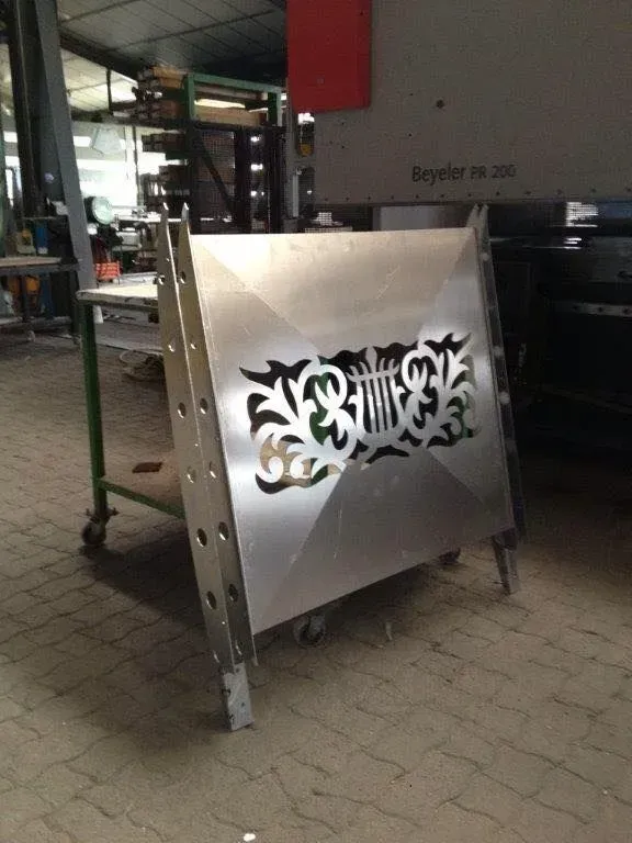 Panneau métallique à motif floral découpé, réalisé en angle en atelier.