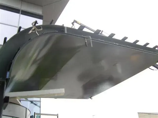 Structure métallique sombre, en forme de pelle inclinée, faisant peut-être partie d'une machine.