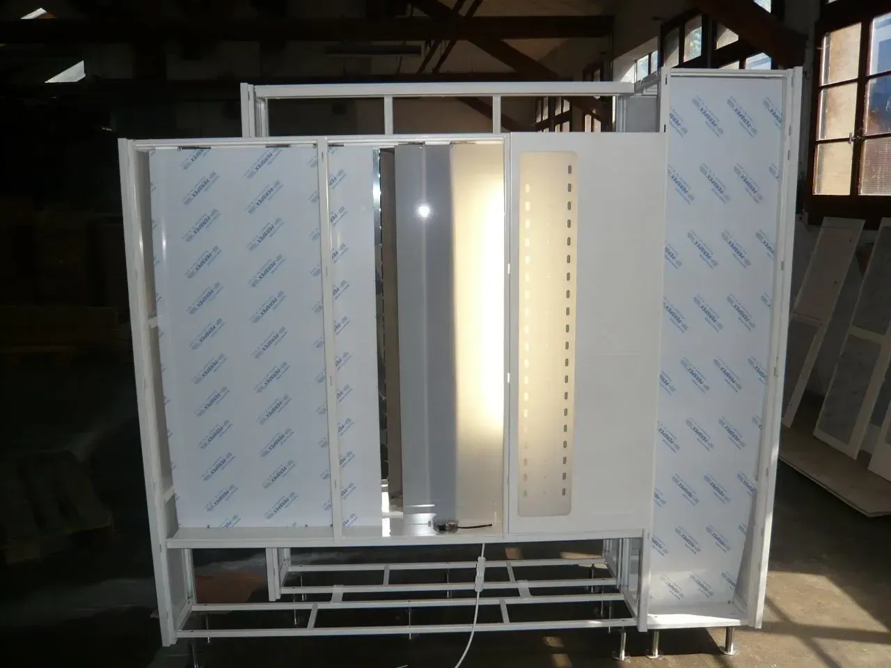 Présentoir en métal blanc avec plusieurs panneaux de couleurs et de textures différentes dans un décor d'atelier.