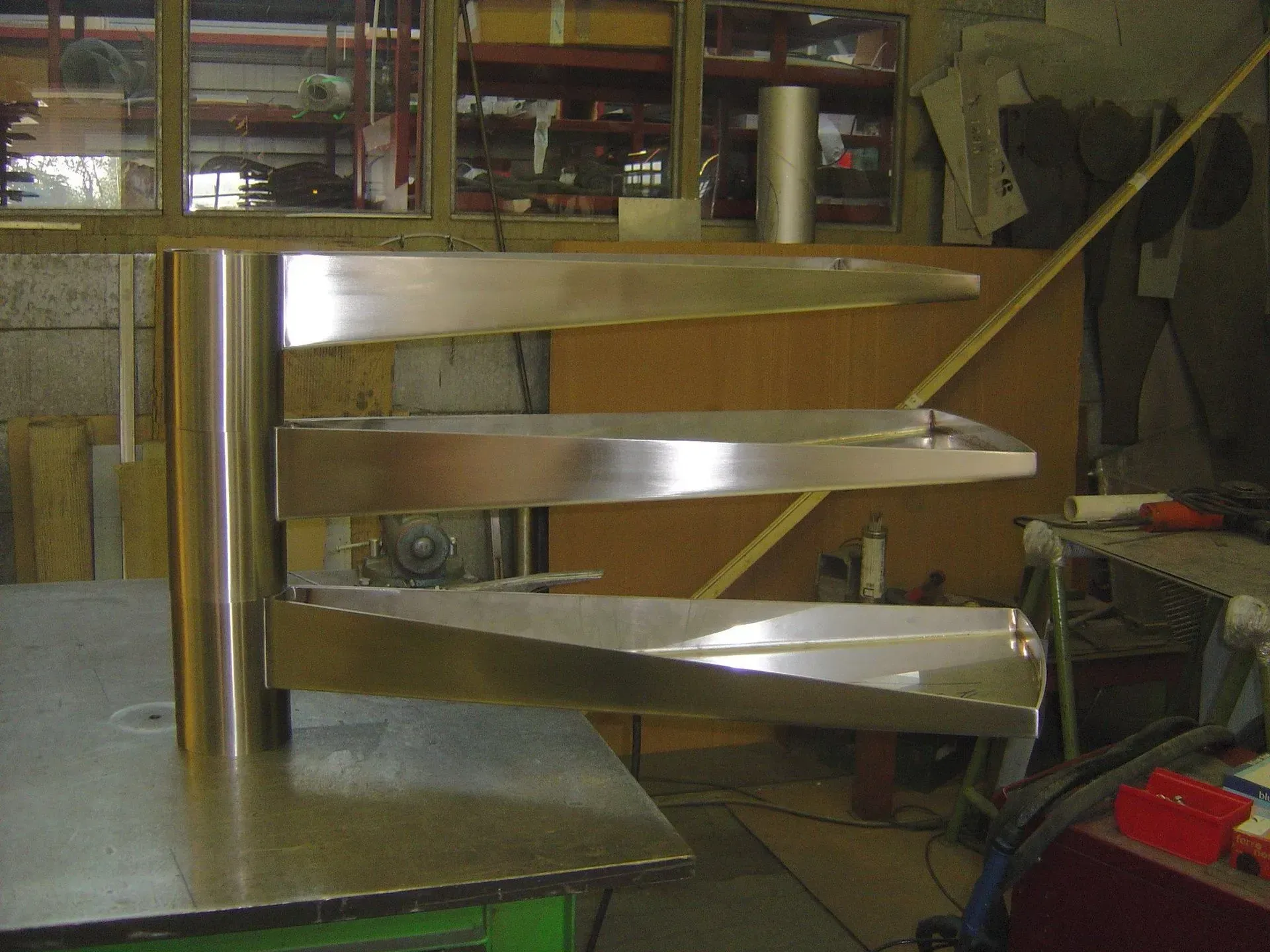 Un modèle d'escalier en colimaçon doré sur une table de travail, présentant une construction avec un poteau cylindrique.