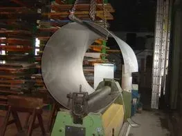 Tôle métallique laminée en cylindre par une machine verte dans un atelier.