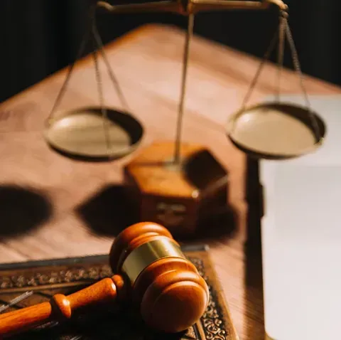 El mazo de un juez está encima de un libro al lado de una balanza de justicia.