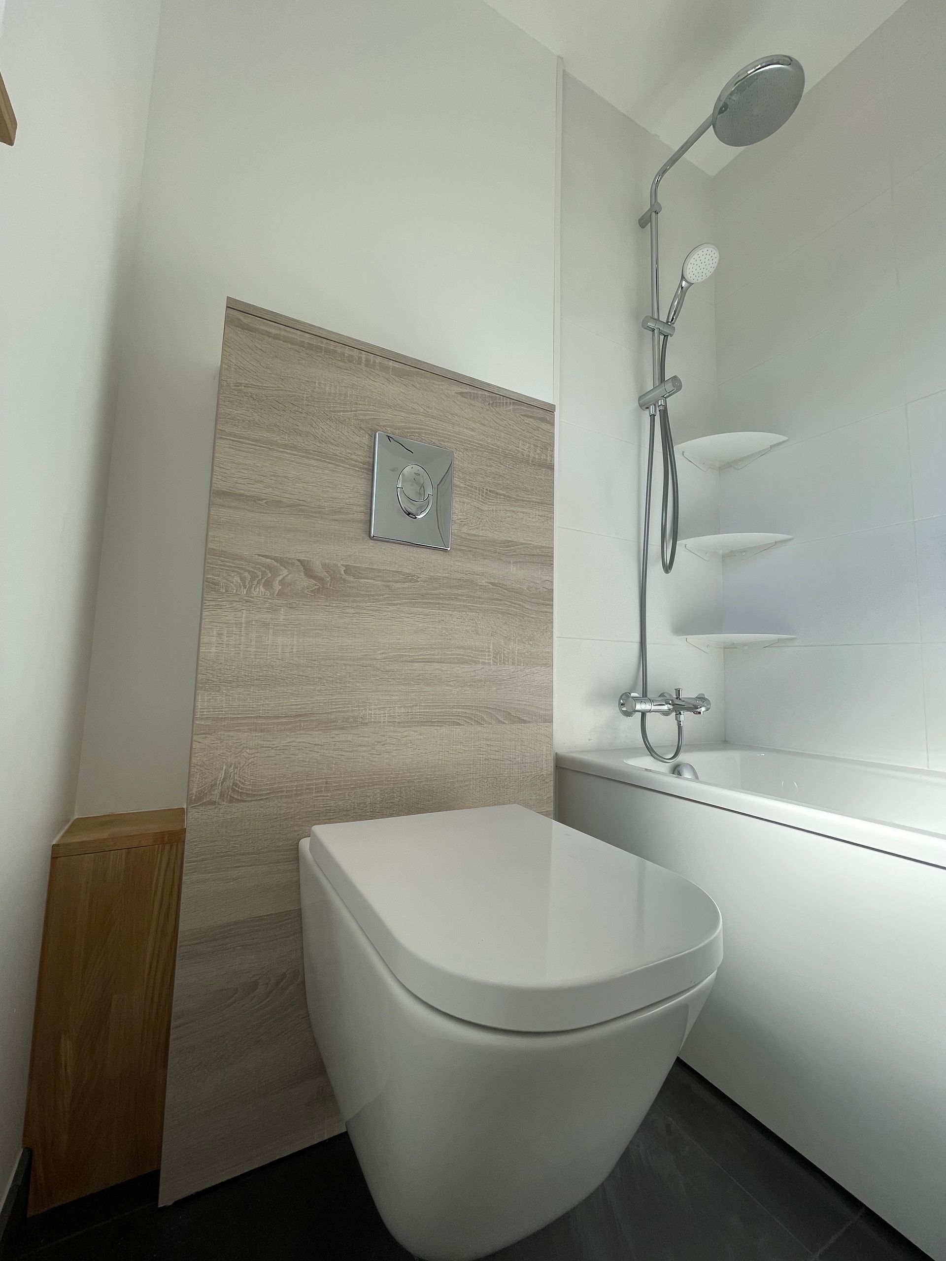 Salle de bains avec toilettes, carrelage mural aux tons neutres, douche et baignoire.