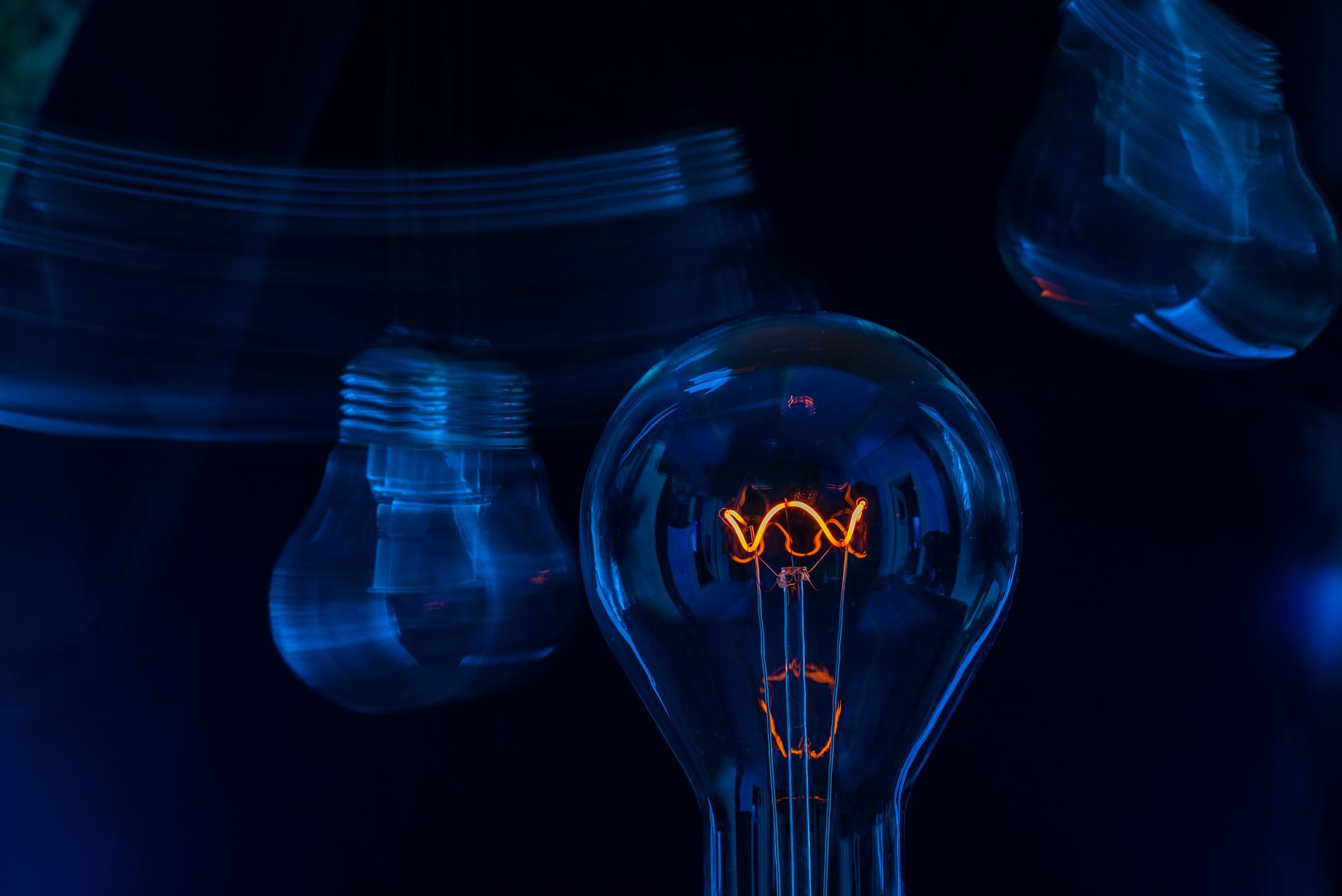Ampoule lumineuse avec les contours flous d'autres ampoules, le tout sur un fond bleu foncé.