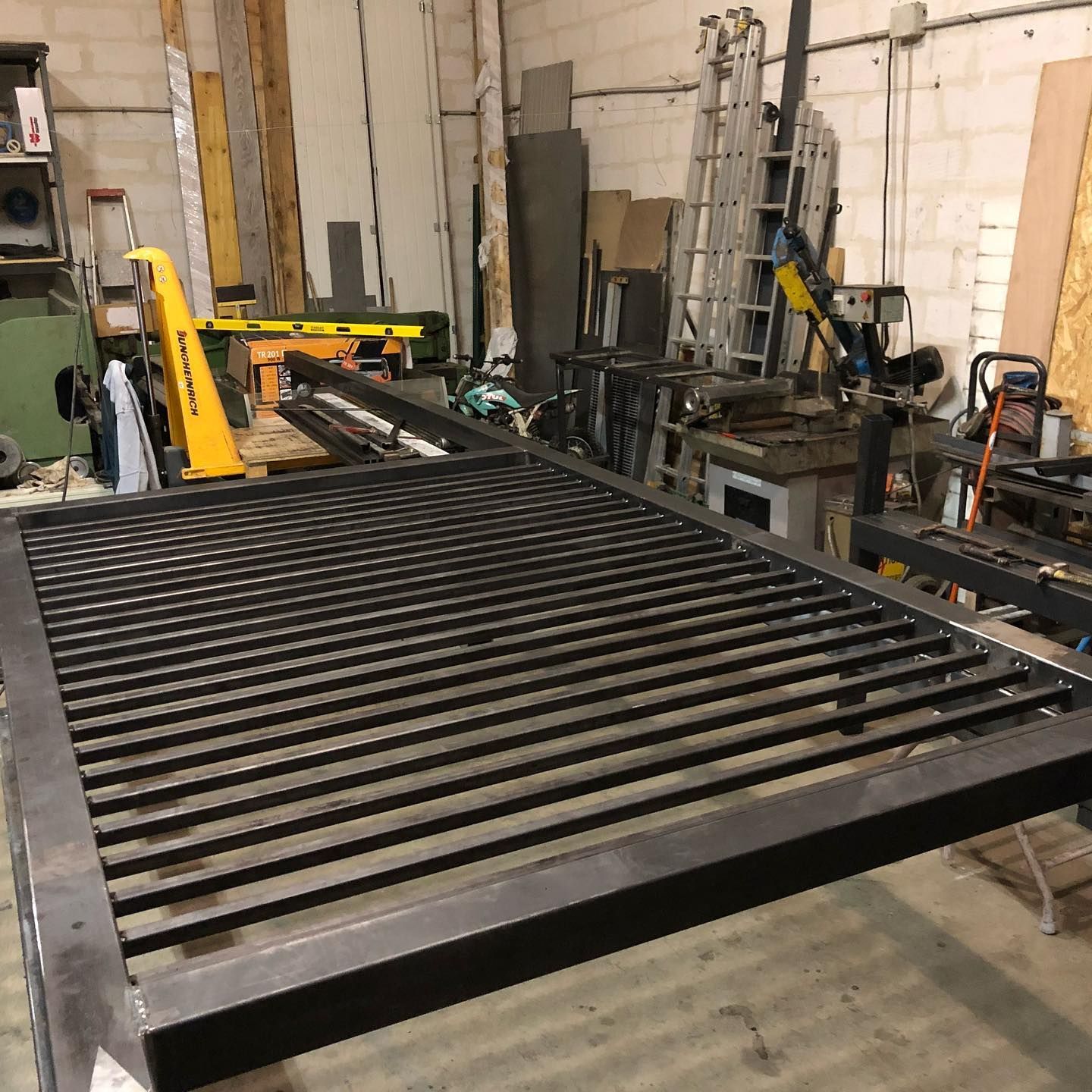 Cadre de portail en métal noir avec barres horizontales dans un atelier.