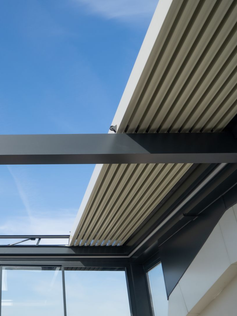 Toit de pergola à lames en aluminium ouvert et réglable avec ciel bleu.