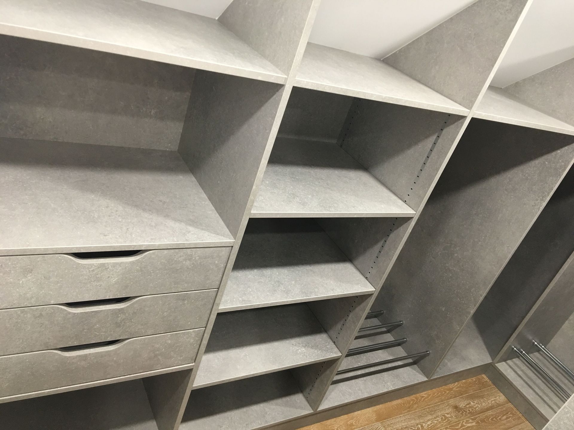 Étagères et tiroirs gris pour placard, avec plusieurs compartiments.