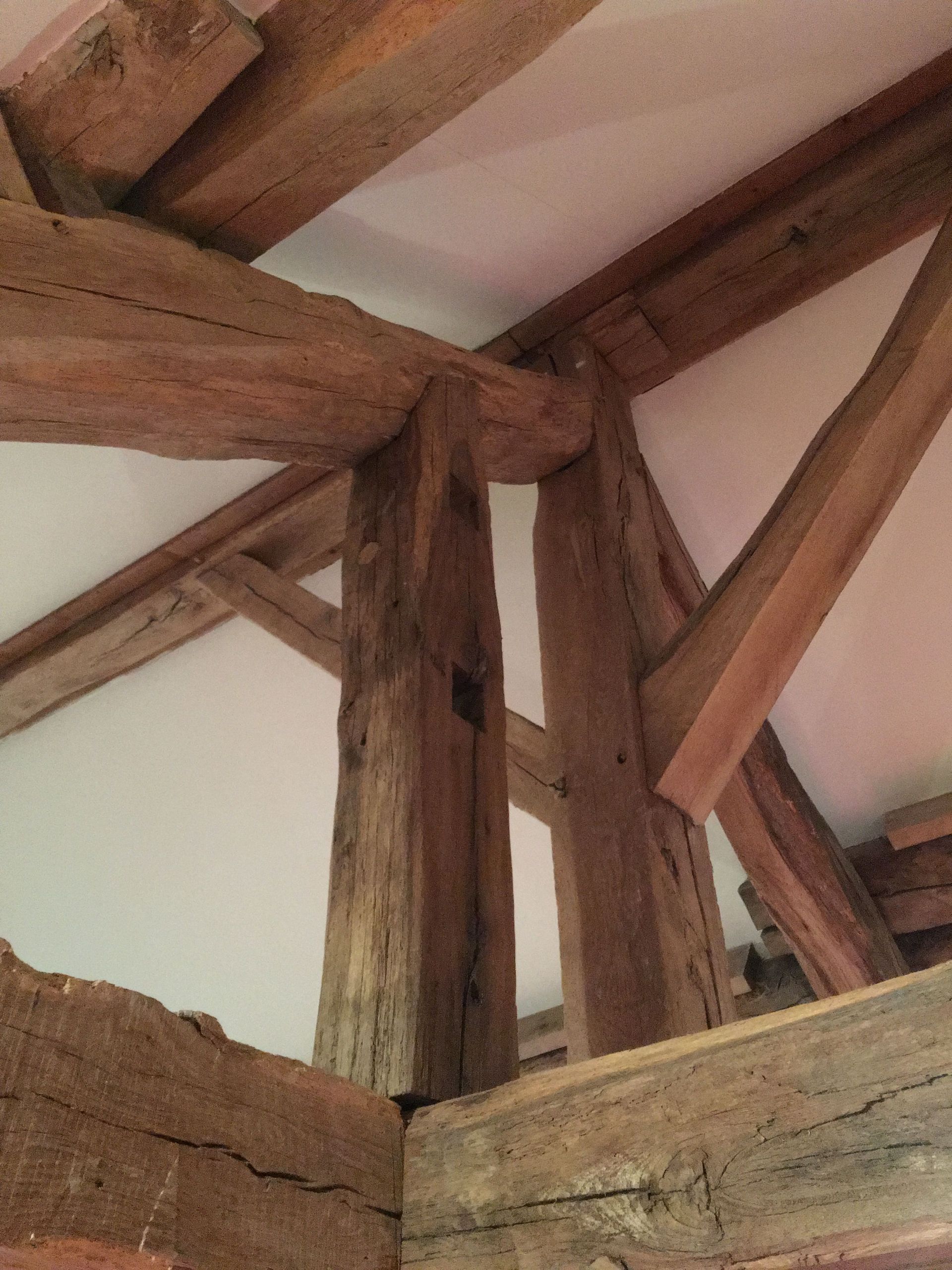 Poutres en bois soutenant un plafond blanc à l'intérieur d'un bâtiment.