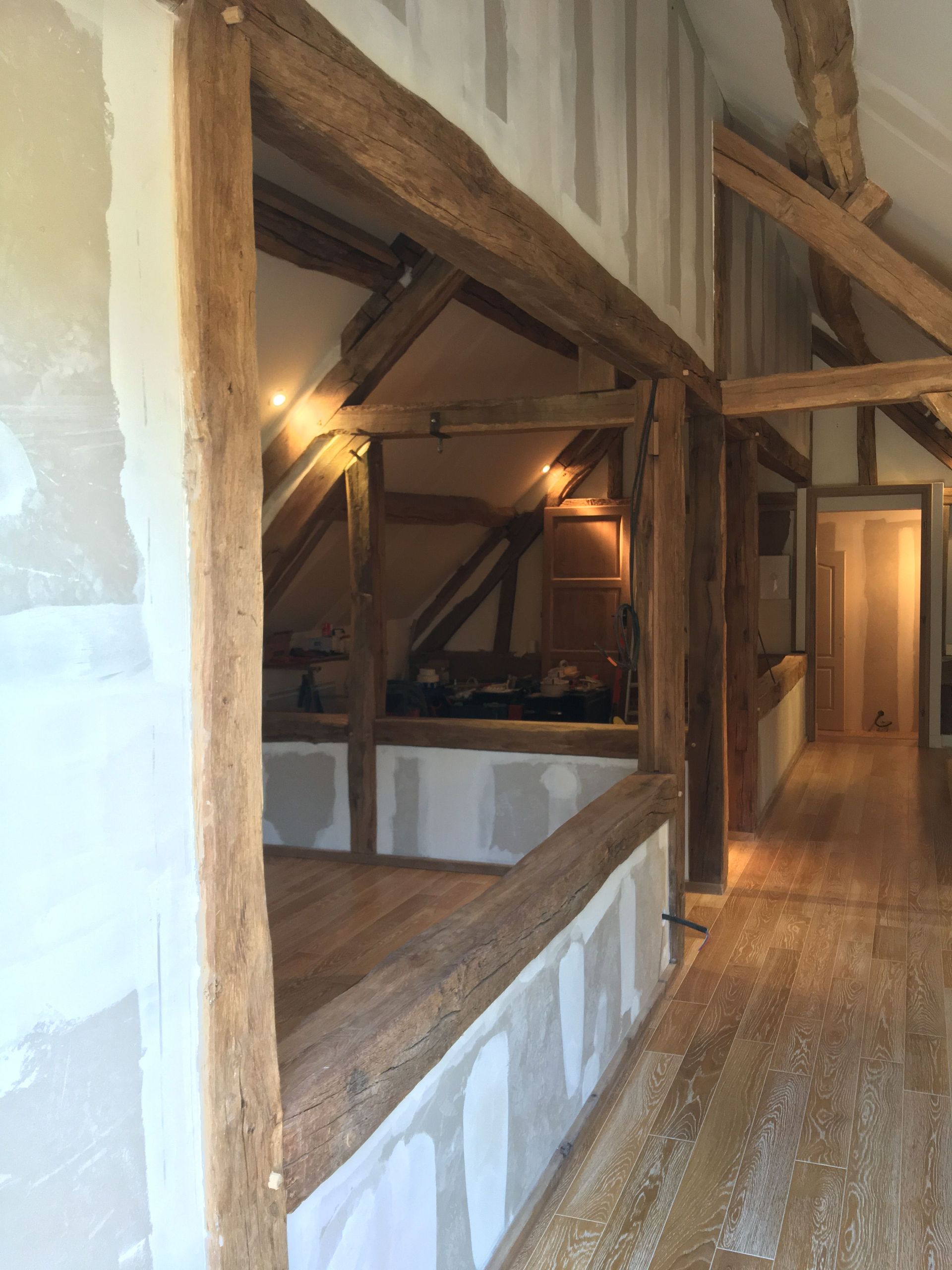 Vue intérieure d'un bâtiment à ossature bois, avec poutres apparentes, cloisons sèches et plancher en bois.
