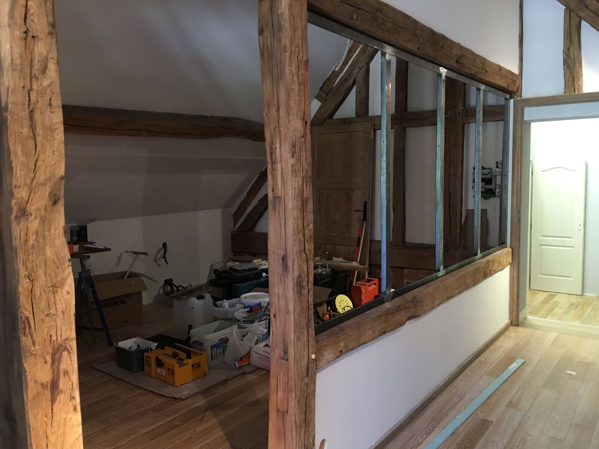Rénovation intérieure avec poutres en bois apparentes, cloisons sèches et ossature métallique.