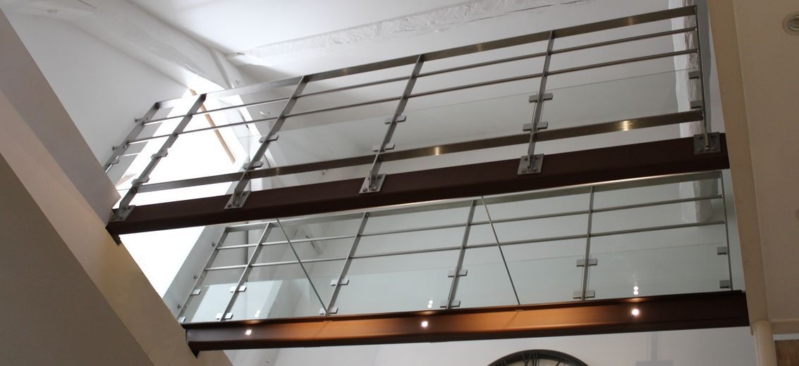 Vue intérieure d'un bâtiment avec un garde-corps avec ossature métallique et parois en verre.
