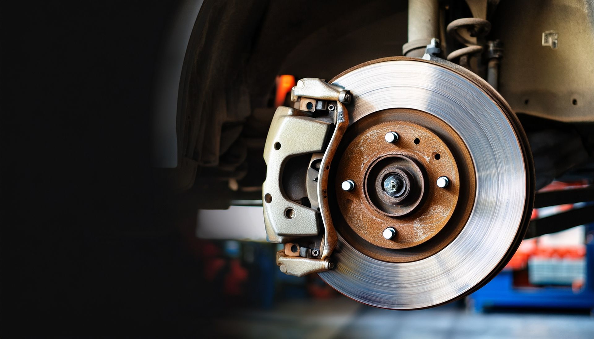 Disque et étrier de frein de voiture dans un garage, gros plan sur un moyeu de roue et un ensemble de freins à disque.