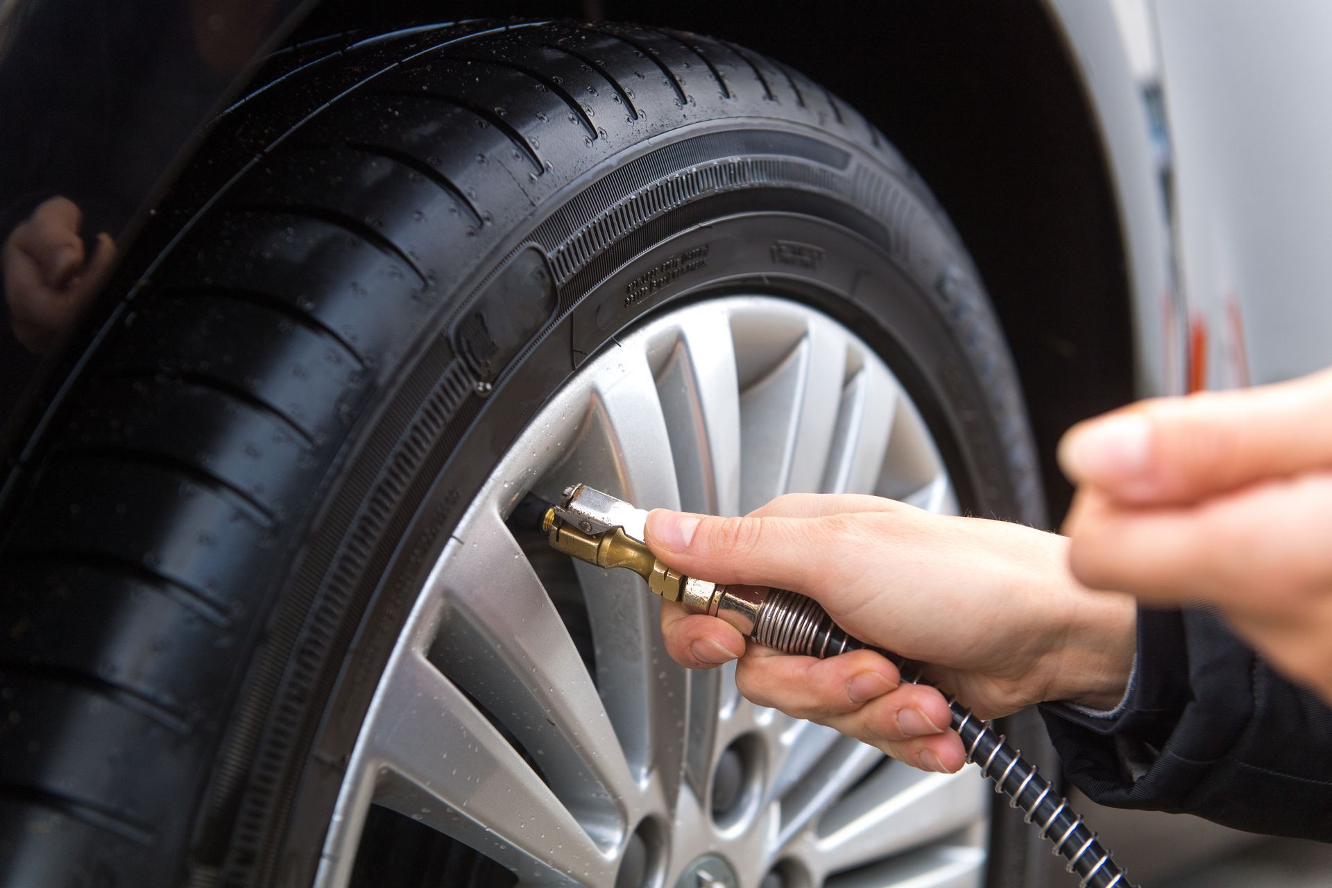 Vérification manuelle de la pression d'un pneu de voiture à l'aide d'un manomètre.