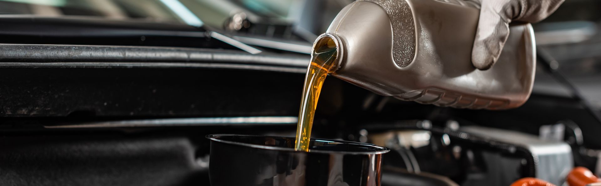 De l'huile moteur est versée d'une bouteille dans le compartiment moteur.