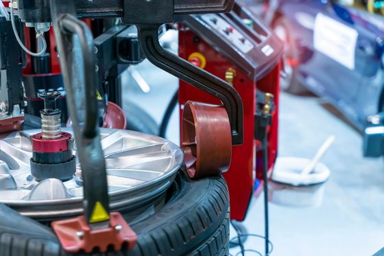Un pneu de voiture est monté sur une machine à pneus rouge dans un atelier automobile.