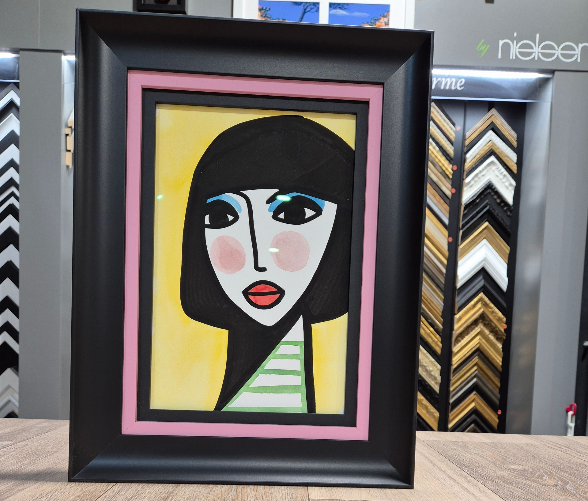 Un portrait stylisé d'une personne avec une coupe au carré, dans un cadre noir à bordure intérieure rose.