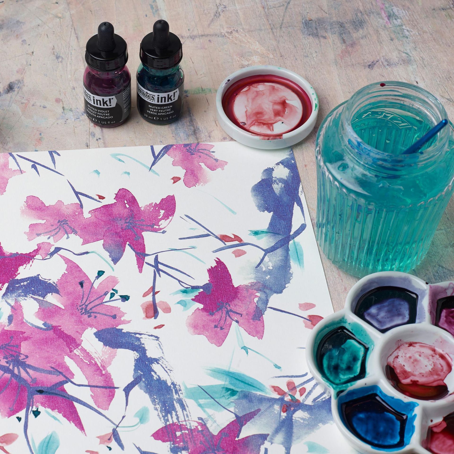 Matériel pour la peinture à l'aquarelle : dessin floral, encres, palette, pot d'eau.