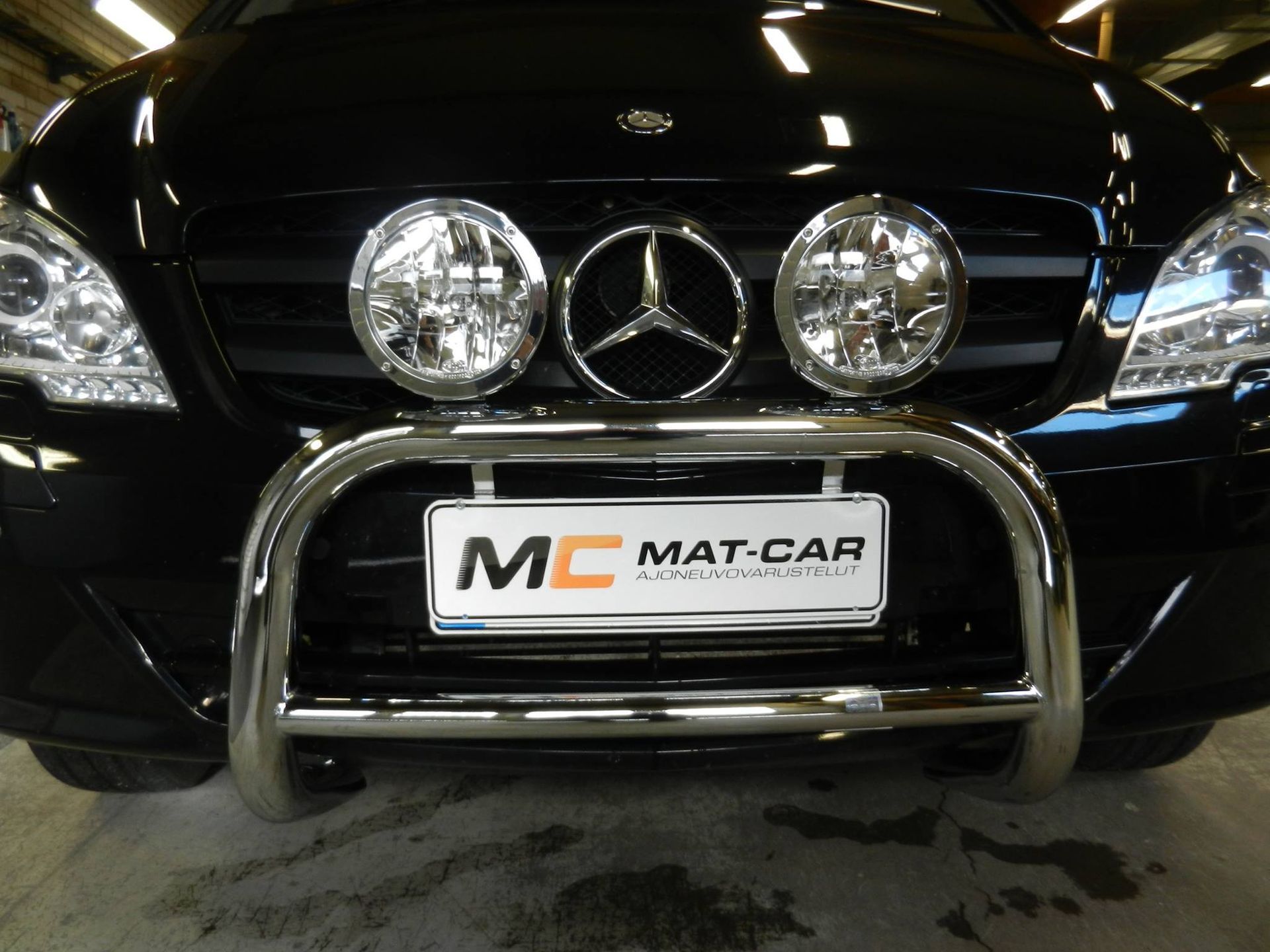 Mustan Mercedes-Benzin etunäkymä, jossa on kromattu säleikkö ja MAT-CAR-rekisterikilpi.