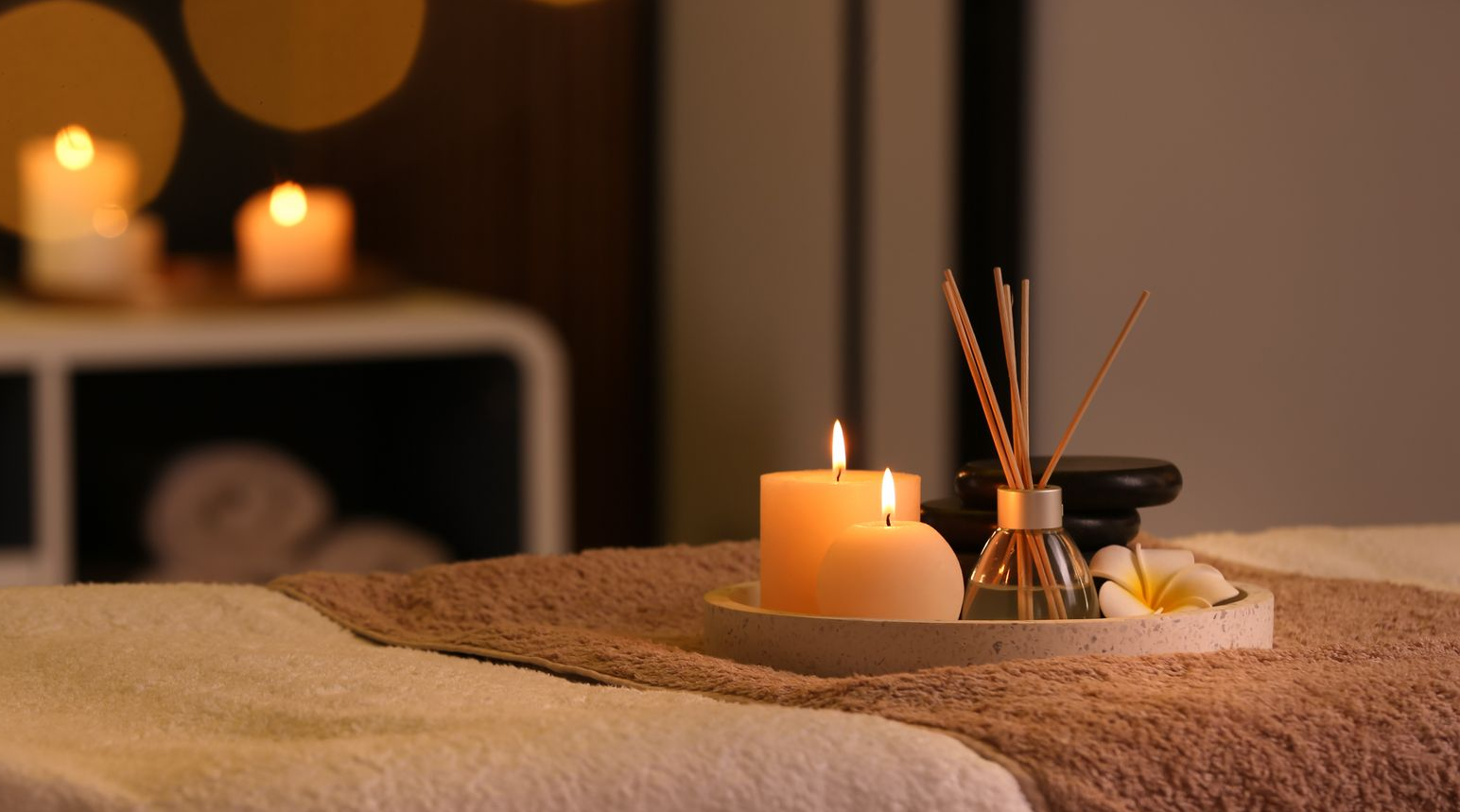 Scène de spa zen avec des cloisons représentant des pierres et des fleurs, une fontaine, des plantes et un mur rouge.