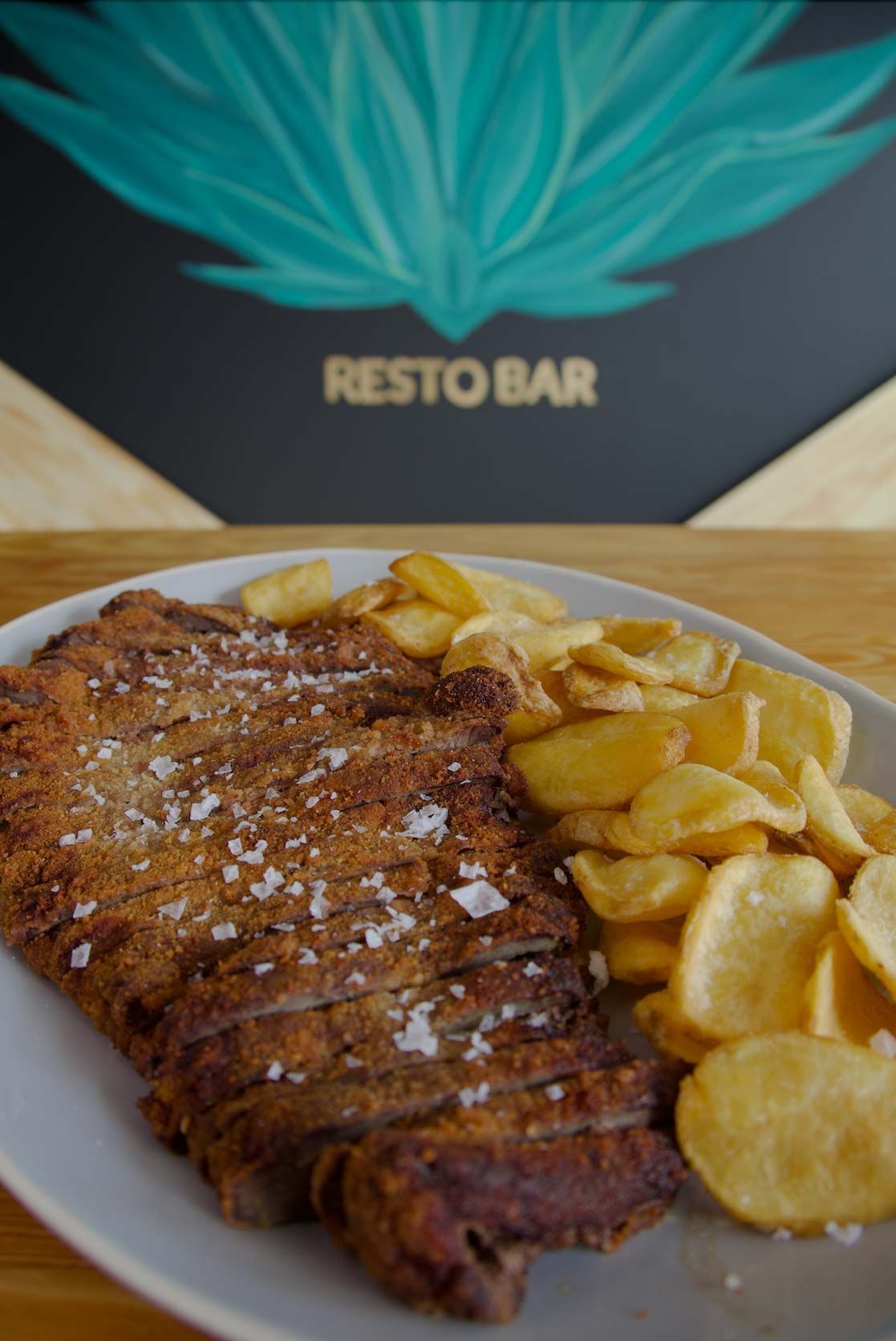 Un plato de comida con un filete y patatas fritas en una mesa.